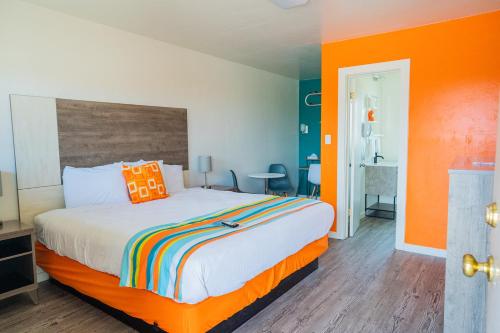 um quarto com uma cama com uma parede laranja em The Atomic Blue Motor-Inn em Monticello