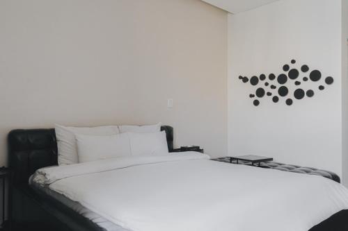 a white bed with a black headboard and a clock on the wall at ACC Design Hotel in Gwangju