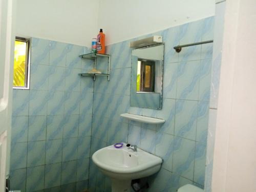 a blue tiled bathroom with a sink and a mirror at HEBERTOGO TOKOIN CASABLANCA in Lomé