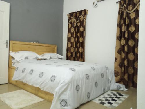 um quarto com uma cama branca e piso em xadrez em HEBERTOGO TOKOIN CASABLANCA em Lomé