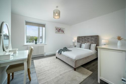 a white bedroom with a bed and a desk and a desk at Luxury Brighton Apartments in Brighton & Hove