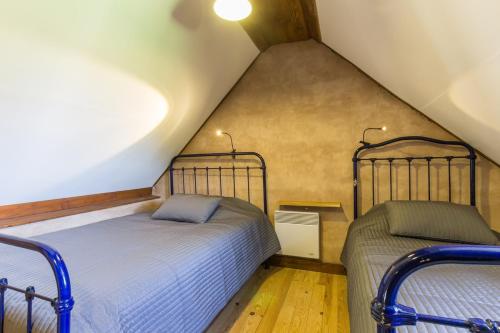 a attic bedroom with two beds in a attic at Chaleureux gîte aux portes de l'histoire in Agy