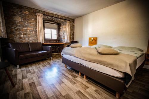 a bedroom with a large bed and a chair at Schmiede Hotel in Schoenberg