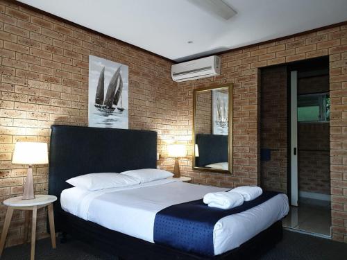 a bedroom with a large bed in a brick wall at Pacific Paradise Airport Motel in Pacific Paradise 