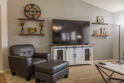 uma sala de estar com uma televisão de ecrã plano e uma cadeira em Cozy home with pool, fire table, BBQ, RV parking em Mesa