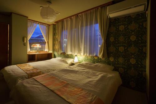 1 dormitorio con 2 camas y ventana en 一棟貸切 Cozy inn Saki -Family & Cyclists Welcome - en Matsumoto