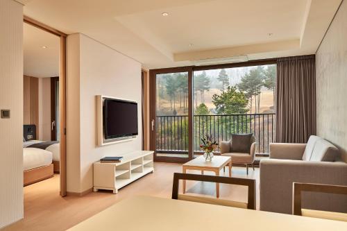 a living room with a couch and a tv and a balcony at Lotte Buyeo Resort in Buyeo