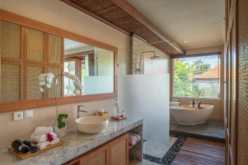 a bathroom with two sinks and two mirrors at Budhi Ayu Villas and Cottages Ubud by Mahaputra-CHSE Certified in Ubud