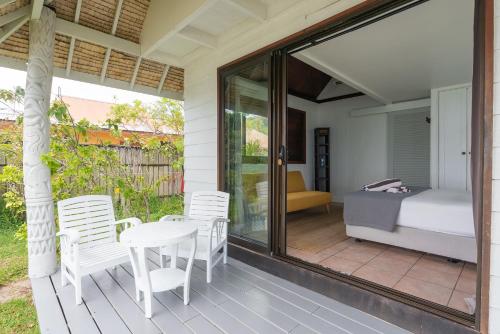 a room with a bed and a table and chairs on a porch at Moorea Island Beach Hotel in Moorea