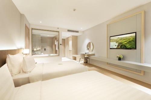 a white hotel room with a bed and a window at DQua Hotel in Nha Trang