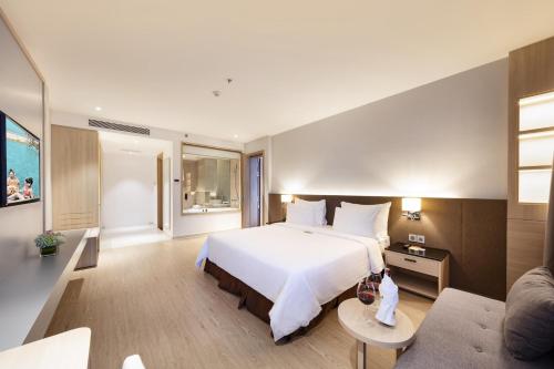 a bedroom with a large white bed and a couch at DQua Hotel in Nha Trang