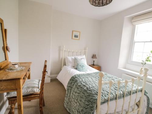 a bedroom with a bed and a table and a window at Beckside Cottage in Welton