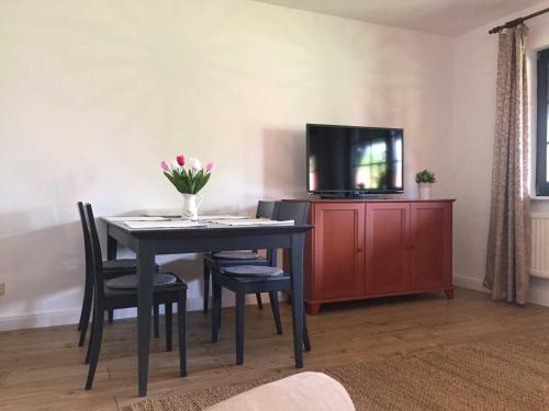 a dining room table with a tv and a vase of flowers at Landpension Dubnitz Landpension Dubnitz - Ferienwohnung 8 