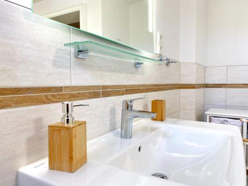 a white bathroom with a sink and a mirror at Reethaus Vilmnitz - Ferienwohnung Vilm in Vilmnitz