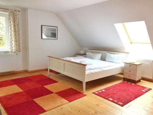 1 dormitorio con cama blanca y alfombra roja en Gutshof Dubnitz -Ferienwohnung 9 " Elsa ", en Dubnitz