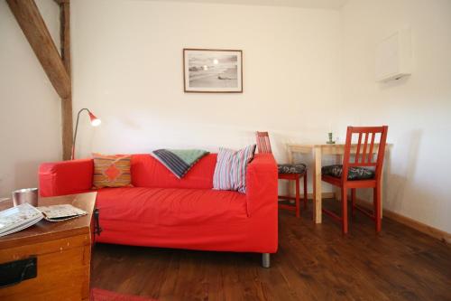 ein Wohnzimmer mit einem roten Sofa und einem Tisch in der Unterkunft Gutshof Dubnitz Gutshof Dubnitz -Ferienwohnung 4 " Anna " 