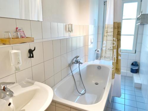 ein weißes Badezimmer mit einer Badewanne und einem Waschbecken in der Unterkunft Sassnitz - Seaside Appartements Seaside Appartements, "Grey" in Sassnitz