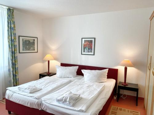 um quarto com uma cama grande com lençóis brancos e almofadas em Appartements am Rondell Neddesitz, Appartement 307 em Neddesitz