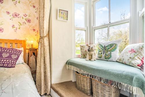 a bedroom with a window and a bench with pillows at Wayside Cottage in Darlington