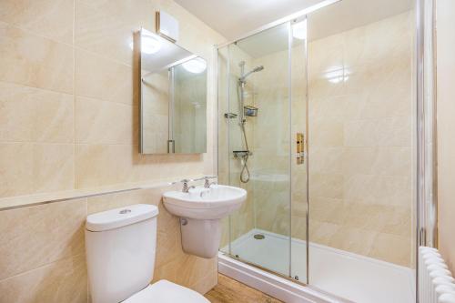 a bathroom with a toilet and a shower and a sink at Wayside Cottage in Darlington