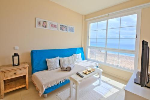 a living room with a blue couch and a window at Playa Paraiso in Costa Calma