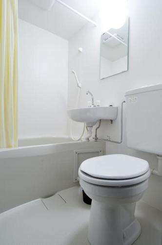 a white bathroom with a toilet and a sink at Keimei Guest House in Osaka