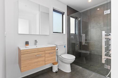 La salle de bains est pourvue d'un lavabo, de toilettes et d'une douche. dans l'établissement Tuturu Bliss - Ruakākā Holiday Home, à Ruakaka