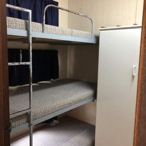 a room with two bunk beds and a refrigerator at Parkes Country Cabins in Parkes