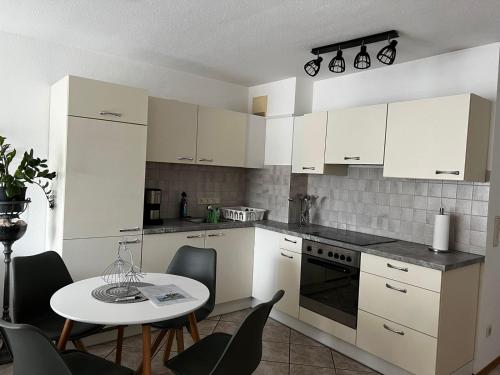 a kitchen with white cabinets and a table with chairs at Cityapartment direkt am Hafen in Friedrichshafen