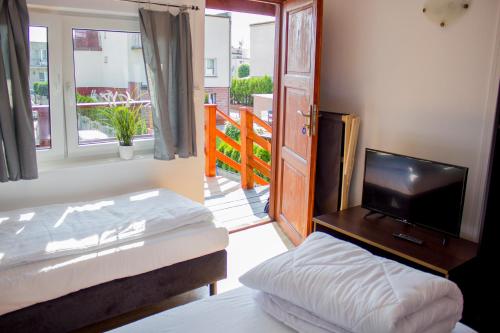 a bedroom with two beds and a television and a balcony at Willa Bryza Rewa in Rewa
