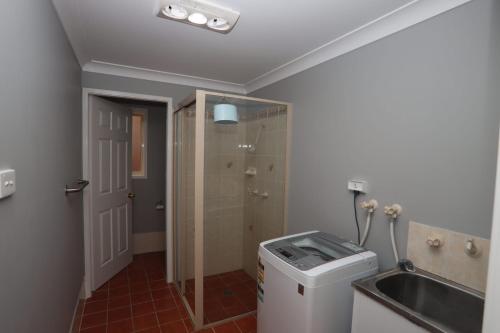 a bathroom with a shower and a sink and a trash can at Fair Views in Sussex inlet