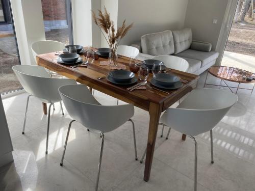 a dining room table with white chairs and a couch at Villa Norda Dębki in Dębki