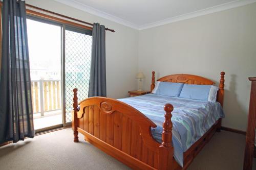 1 dormitorio con cama de madera y ventana grande en Perfect family holiday, en Berrara