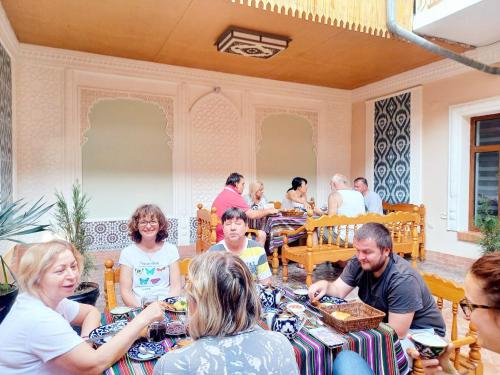 a group of people sitting at tables in a restaurant at Hotel Nasriddin Navruz in Bukhara