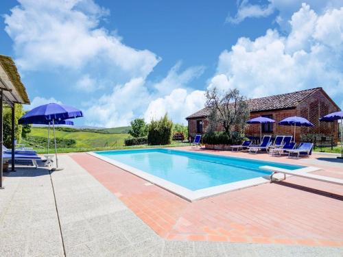 ein Pool mit Sonnenschirmen und Stühlen sowie ein Haus in der Unterkunft Belvilla by OYO Orchidea Primo Piano in Peccioli