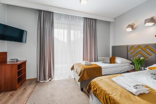 a hotel room with two beds and a flat screen tv at Hotel Smile Pieniny in Szczawnica