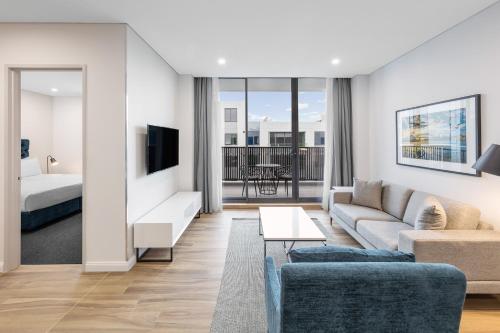 a living room with a couch and a bed at Meriton Suites Coward Street, Mascot in Sydney