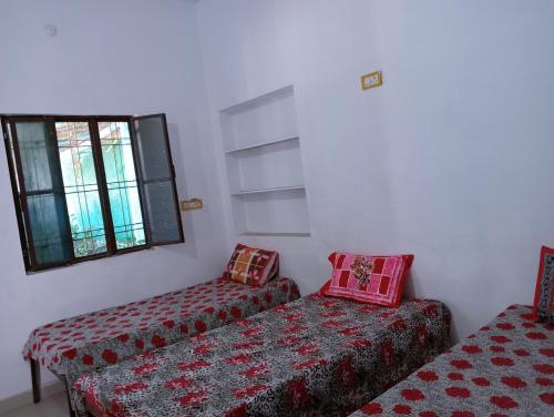 een kamer met twee bedden en een bank en een raam bij Veera's Hostel in Pushkar