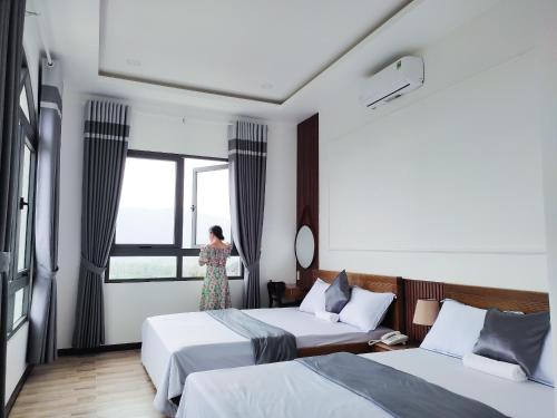 a woman standing in a hotel room with two beds at Hotel Hoa Nắng in Bao Loc