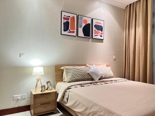 a bedroom with a bed and three paintings on the wall at Fairview Luxury Apartments in Dar es Salaam