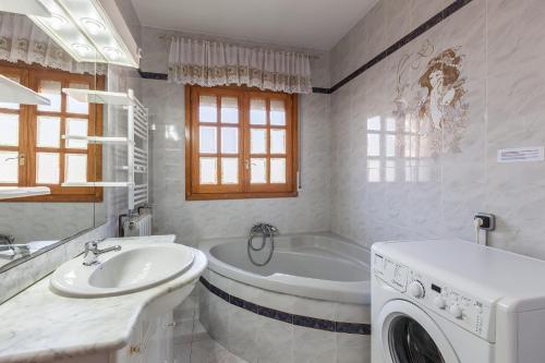 a bathroom with a tub and a sink and a washing machine at Villa Gessami in Barcelona