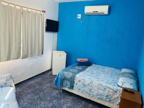 a room with a bed and a blue wall at Suites Moreninha in Rio de Janeiro