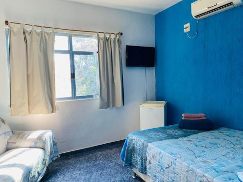 a blue room with a bed and a window at Suites Moreninha in Rio de Janeiro