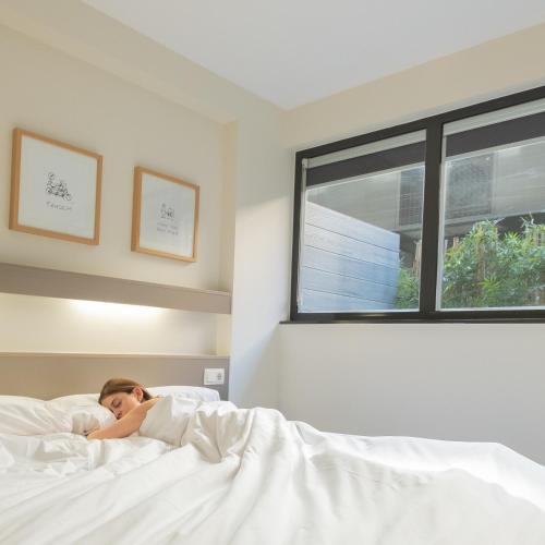 a woman laying in bed in a bedroom at Aparthotel Bcn Montjuic in Barcelona