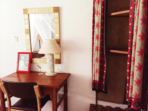 a room with a table and a lamp and a mirror at Utupoa in Matemwe