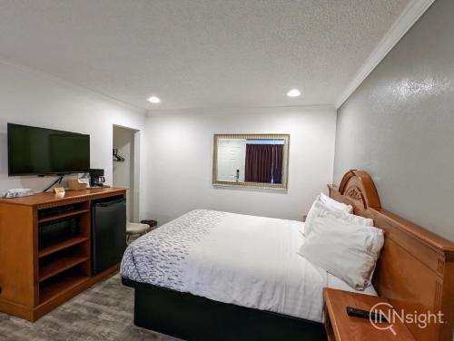 a bedroom with a bed and a flat screen tv at Deluxe Inn in South San Francisco