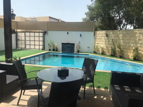 a swimming pool with a table and chairs next to it at Yacob's The Nest in Ajman 