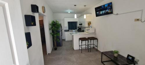 Una cocina con encimera y taburetes en una habitación. en GATED AND VERY SECURED WHITE HOUSE 6 MINS FROM THE BEACH, en Puerto Peñasco