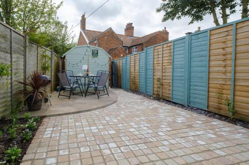 a patio with a table and chairs next to a fence at Hazel's in Leiston