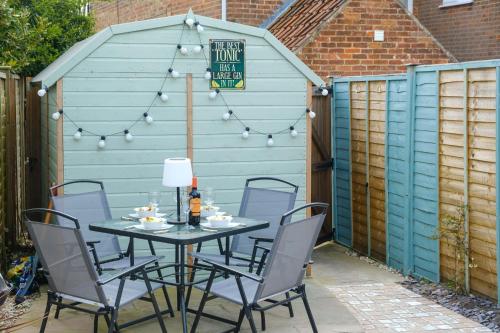 a patio with a table and chairs in front of a shed at Hazel's in Leiston
